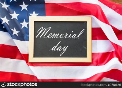 patriotism and national holidays concept - memorial day words on chalkboard and american flag. memorial day words on chalkboard and american flag