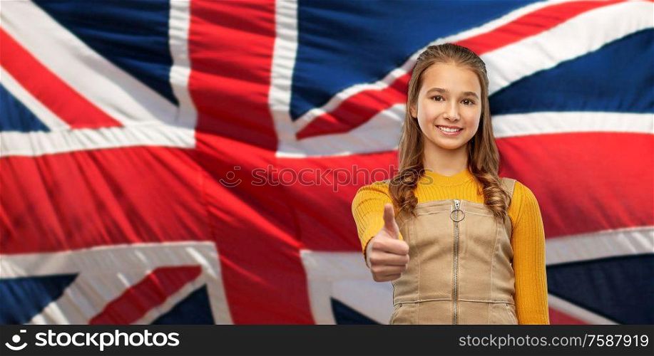 patriotism, gesture and people concept - smiling young teenage girl showing thumbs up over british flag background. teenage girl showing thumbs up over british flag