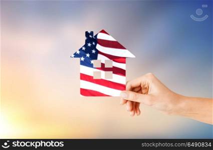 patriotism, home and citizenship concept - hand holding paper house in colors of american flag over evening sky background. hand holding paper house in colors of american flag. hand holding paper house in colors of american flag