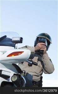 Patrol officer sits on motorcycle looking through speedometer