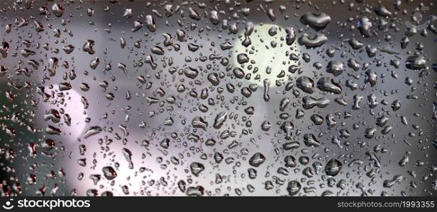 pattern of rain drops on glass window and colorful diffuse unsharp lights with