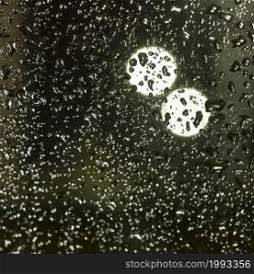 pattern of rain drops on glass window and colorful diffuse unsharp lights with