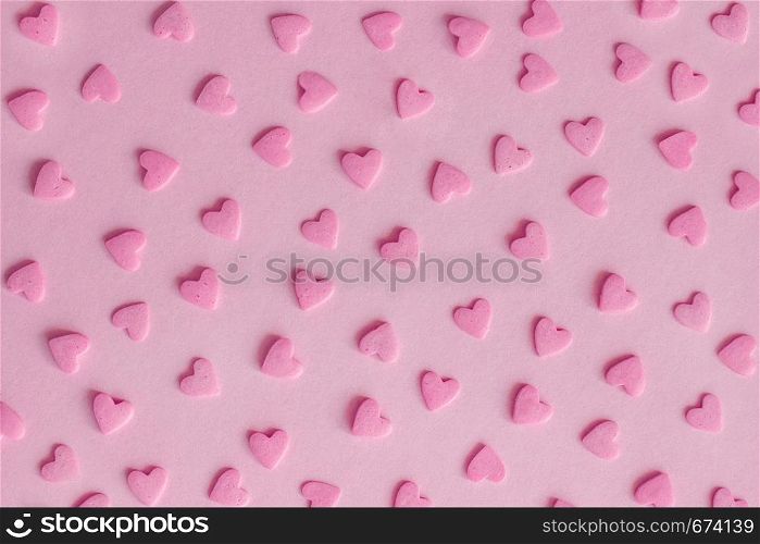 Pattern. Pink confectionery sprinkles in form of hearts on pink background, texture