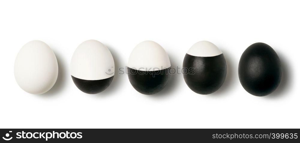 Pattern with row from eggs white and black painted on a white background with place for text. Top view. Concept of dualism yin and yang.. White and black colored eggs on a white background with copy space. Concept of changing life. Flat lay.
