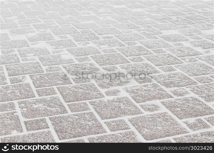 Pavement of red tiles under the frost and snow. Ice in the city, cold weather.