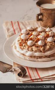 Pavlova cake with caramel and almonds on the wooden background