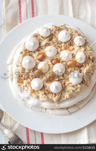 Pavlova cake with caramel and almonds on the wooden background