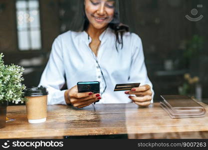 Pay for goods by credit card through a smartphone in a coffee shop.