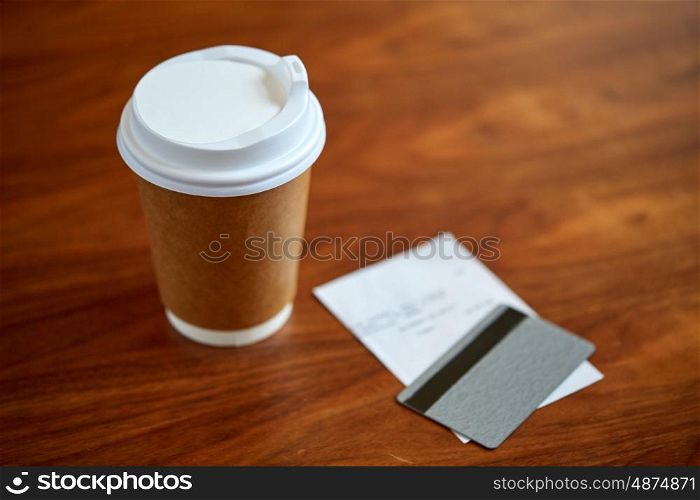 payment and consumerism concept - coffee drink in paper cup, bill and credit card on table