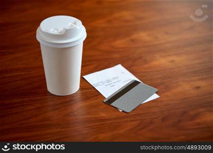 payment and consumerism concept - coffee drink in paper cup, bill and credit card on table