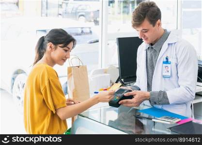 Payment by credit card with payment terminal in qualified drugstore. Modern financial payment of electric money. Satisfied customer purchase medication in pharmacy with prescription from pharmacist.. Satisfied customer purchases qualified prescription medication from pharmacist.