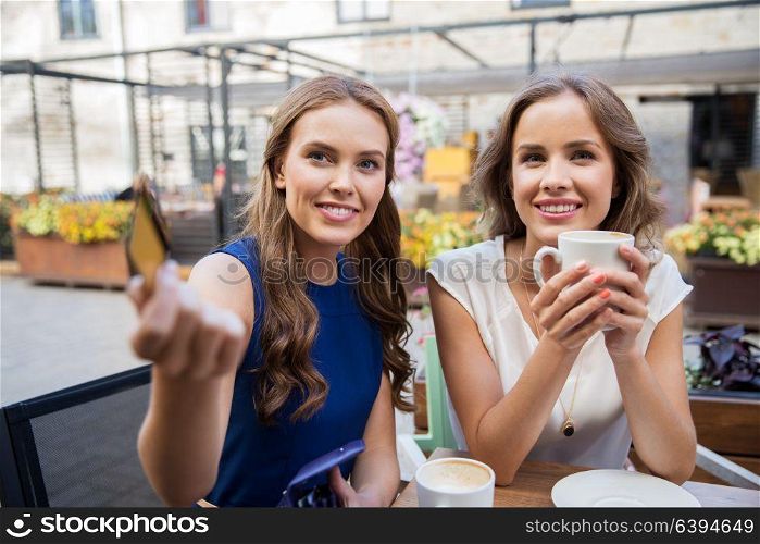 payment, finances and people concept - smiling young women paying for coffee with credit card at street cafe. young women paying for coffee at street cafe