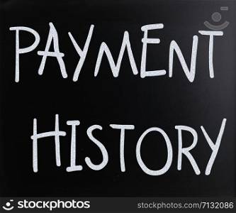 ""Payment history" handwritten with white chalk on a blackboard"