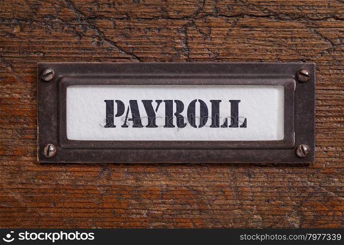 payroll - file cabinet label, bronze holder against grunge and scratched wood, financial concept