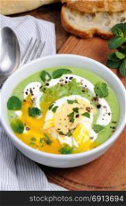 Pea puree soup with poached egg, sour cream, mint leaves seasoned with spices.