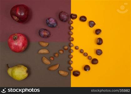 Peace symbol of in shell nuts and autumn fruits on split background