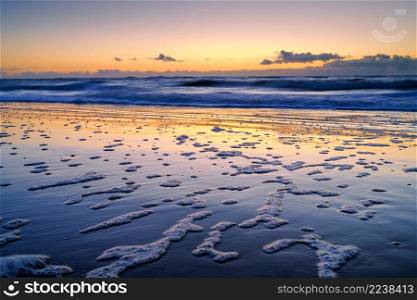 Peaceful and tranquil zen-like sunset on the beach with beautiful reflections on the water - North Sea, Netherlands. Sunset over the ocean on the Dutch Shore, Netherlands, Holland