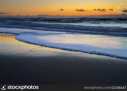 Peaceful and tranquil zen-like sunset on the beach with beautiful reflections on the water - North Sea, Netherlands. Sunset over the ocean on the Dutch Shore, Netherlands, Holland