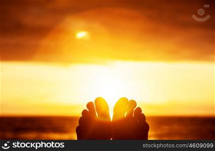 Peaceful beautiful orange sunset, body part, persons toes, carefree lifestyle, summer vacation, harmony and freedom concept
