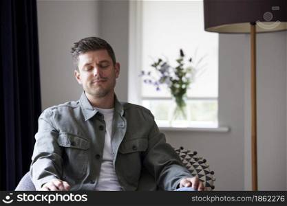 Peaceful Man Meditating Sitting In Chair At Home