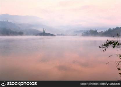 Peaceful place, Pa Khong Lake in morning light in summer season, soft mist covers on the lake and mountains backgrounds. Scenic landscape of Dien Bien District, Vietnam. Warm tone. Shallow dept of field.