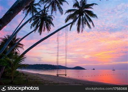 Peaceful time, beautiful clouds and sunset sky. Swing and coconut trees foreground, bay and yacht background. Summer season. Koh Mak Island, Trat, eastern Thailand.