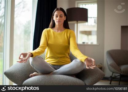 Peaceful Woman Meditating Sitting In Chair At Home