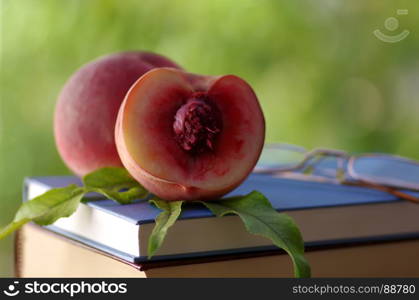 Peach and glasses on book, green background