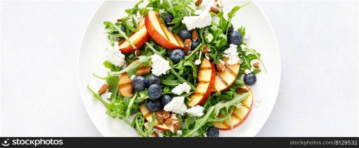 Peach, blueberry and arugula fresh fruit salad with cheese and almond nuts. Top view. Banner