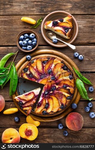 Peach cheese cake or pie with fresh blueberry on wooden rustic background, top view, closeup