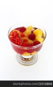 Peach compote with fresh red currants and sour cherries in glass bowl isolated on white