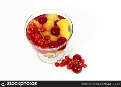 Peach compote with fresh red currants and sour cherries in glass isolated on white