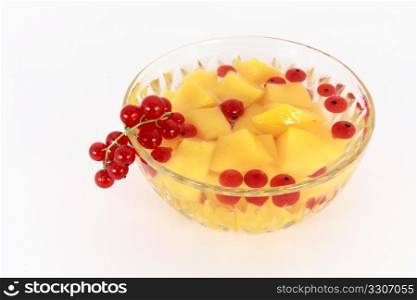Peach compote with fresh red currants in glass bowl isolated on white