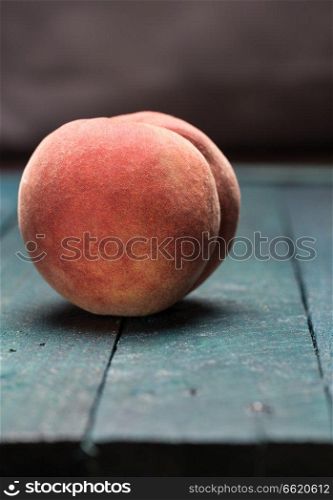Peach on petrol colored wooden background.. Peach on petrol colored wooden background