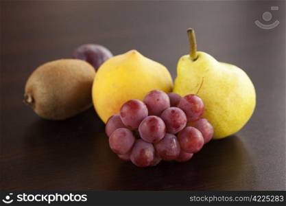 peach, pear,kiwi and grapes lying on a wooden table