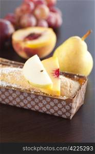 peach, pear, plum, coconut cake, and grapes on a wooden table