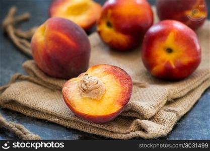 Peaches and nectarines on rustic napkin over dark background, selective focus, closeup
