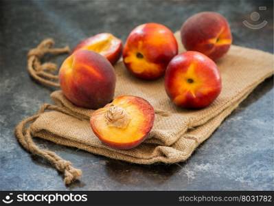 Peaches and nectarines on rustic napkin over dark background, selective focus, closeup