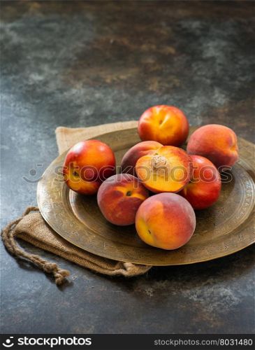 Peaches and nectarines on vintage tray over dark background, selective focus
