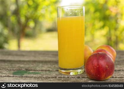 peaches and peach juice on a wooden table, outdoor