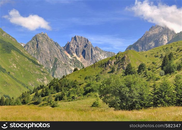 peaks of rocky mountain back green hills in summer