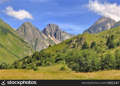 peaks of rocky mountain back green hills in summer