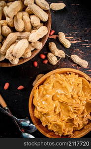 Peanut butter and inshell peanuts in wooden plates. On a rustic dark background. High quality photo. Peanut butter and inshell peanuts in wooden plates.