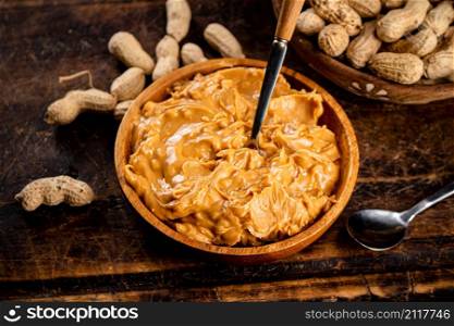 Peanut butter and inshell peanuts on a cutting board. Against a dark background. High quality photo. Peanut butter and inshell peanuts on a cutting board.