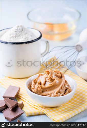 Peanut butter, chocolate chunks, eggs, sugar and cup of flour. Ingredients for baking. Selective focus