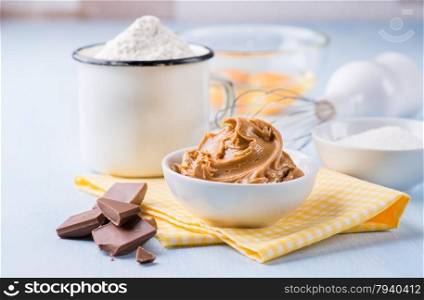 Peanut butter, chocolate chunks, eggs, sugar and cup of flour. Ingredients for baking. Selective focus