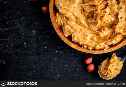 Peanut butter in a plate and spoon. On a black background. High quality photo. Peanut butter in a plate and spoon.