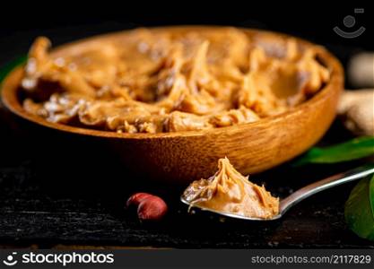 Peanut butter in a plate and spoon. On a black background. High quality photo. Peanut butter in a plate and spoon.