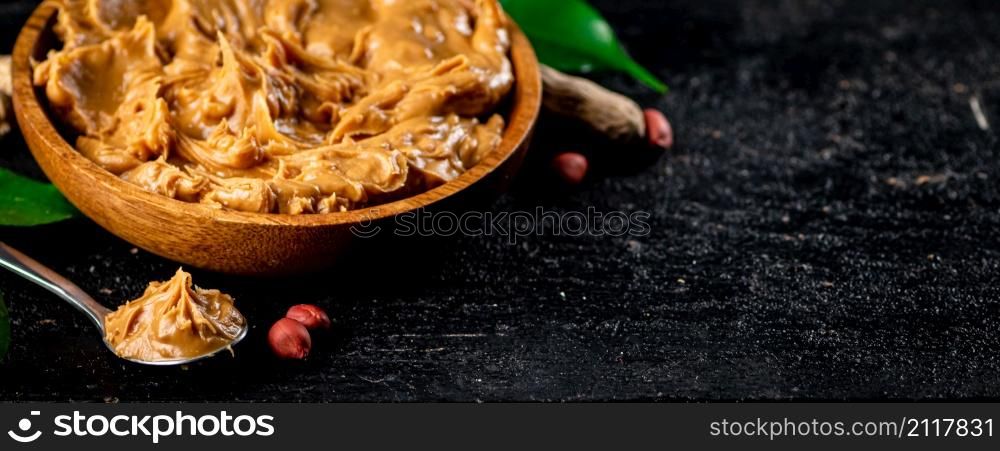 Peanut butter in a plate and spoon. On a black background. High quality photo. Peanut butter in a plate and spoon.