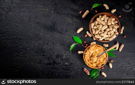 Peanut butter in a wooden plate. On a black background. High quality photo. Peanut butter in a wooden plate.